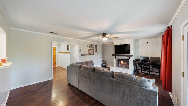 413 E 9th St, Kaufman, TX 75142 - living area with ceiling fan, a brick fireplace, dark wood-style flooring, crown molding, and baseboards