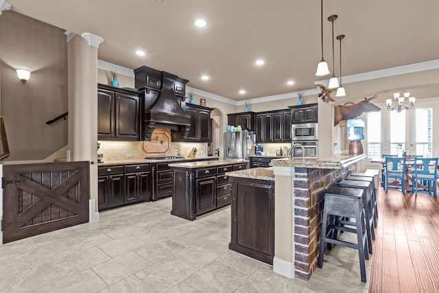 781 Audra Cir, Rhome, TX 76078 - kitchen with an island with sink, crown molding, a chandelier, appliances with stainless steel finishes, and premium range hood