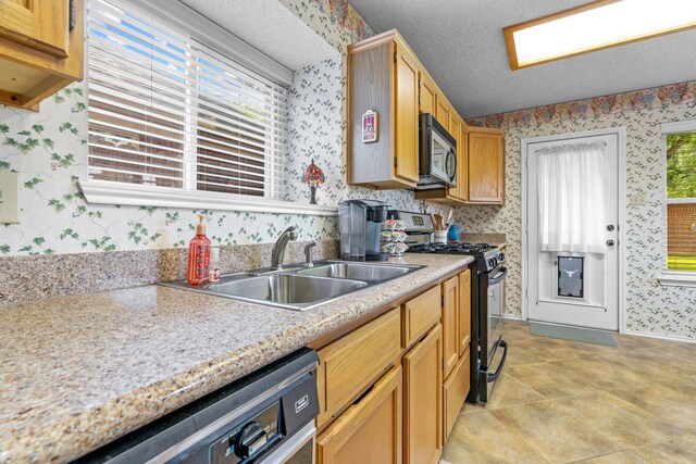 5502 Misty Crest Dr, Arlington, TX 76017 - kitchen with gas stove, wallpapered walls, dishwasher, light countertops, and a sink