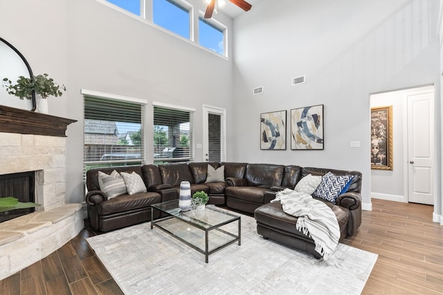 1319 Bridgewater Blvd, Celina, TX 75009 - living area featuring a towering ceiling, a ceiling fan, wood finished floors, a stone fireplace, and baseboards