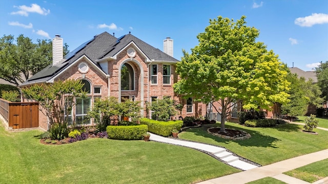 8405 Dawson Dr, Plano, TX 75025 - view of front facade featuring a chimney, brick siding, roof mounted solar panels, and a front yard