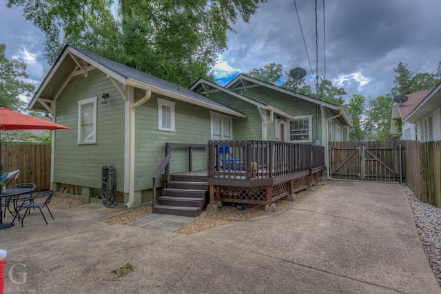 rear view of house with a gate, a deck, fence, and a patio