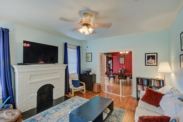 living room with ceiling fan, ornamental molding, wood finished floors, a chandelier, and a fireplace with flush hearth