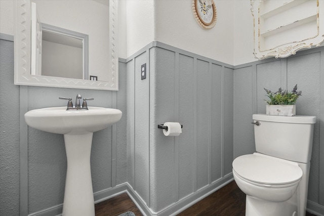 7608 White Fawn Rd, Arlington, TX 76002 - bathroom featuring wood finished floors, toilet, a wainscoted wall, and a sink