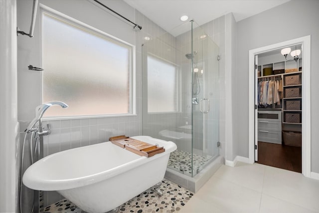7608 White Fawn Rd, Arlington, TX 76002 - bathroom with a shower stall, a walk in closet, a freestanding bath, tile patterned flooring, and tile walls