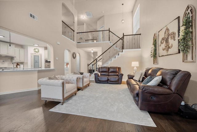 7608 White Fawn Rd, Arlington, TX 76002 - living room with arched walkways, a high ceiling, dark wood-style floors, stairway, and baseboards