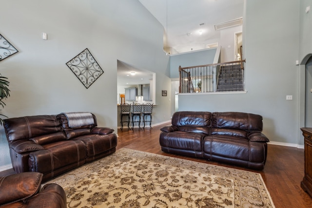 living area with wood finished floors, baseboards, and a high ceiling