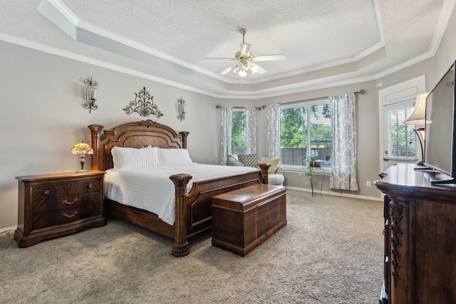bedroom featuring a raised ceiling, a textured ceiling, ornamental molding, light colored carpet, and a ceiling fan
