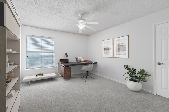 carpeted office space with a ceiling fan, a textured ceiling, and baseboards