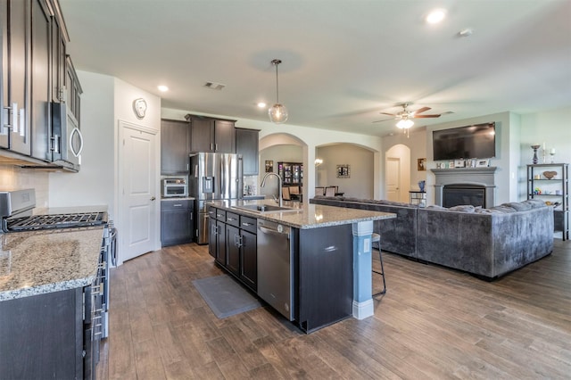 11312 Culberson Dr, Aubrey, TX 76227 - kitchen with stainless steel appliances, a sink, a ceiling fan, dark wood-style flooring, and arched walkways