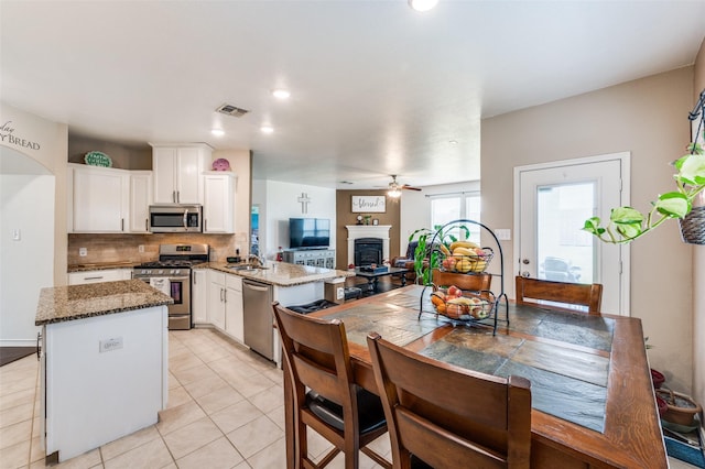 820 Lake Sierra Way, Little Elm, TX 75068 - kitchen featuring stainless steel appliances, white cabinetry, a ceiling fan, backsplash, and a kitchen island