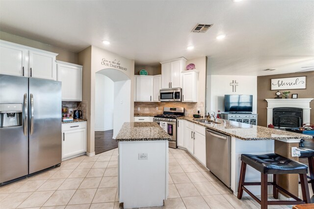 820 Lake Sierra Way, Little Elm, TX 75068 - kitchen with appliances with stainless steel finishes, a peninsula, backsplash, a kitchen island, and stone countertops