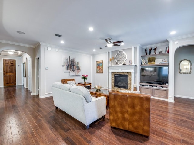13026 Brook Ridge Dr, Frisco, TX 75035 - living area with arched walkways, a ceiling fan, a glass covered fireplace, dark wood-type flooring, and ornamental molding