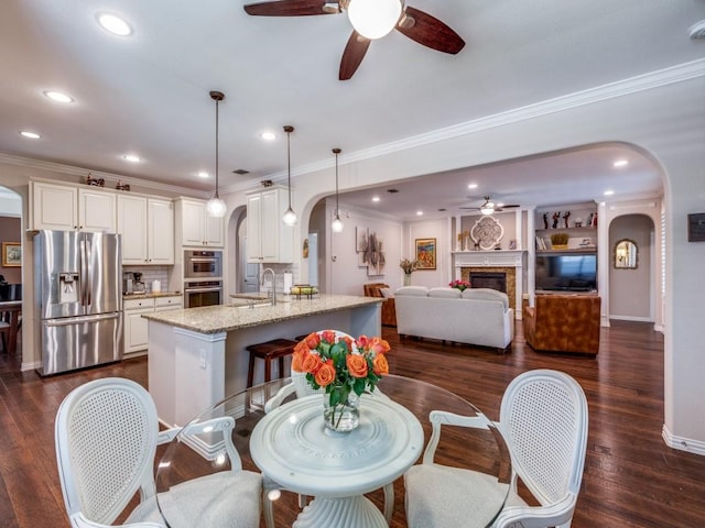 13026 Brook Ridge Dr, Frisco, TX 75035 - dining room featuring arched walkways, ceiling fan, crown molding, dark wood-type flooring, and recessed lighting