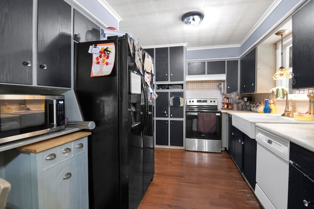 kitchen with appliances with stainless steel finishes, a sink, dark wood finished floors, and crown molding