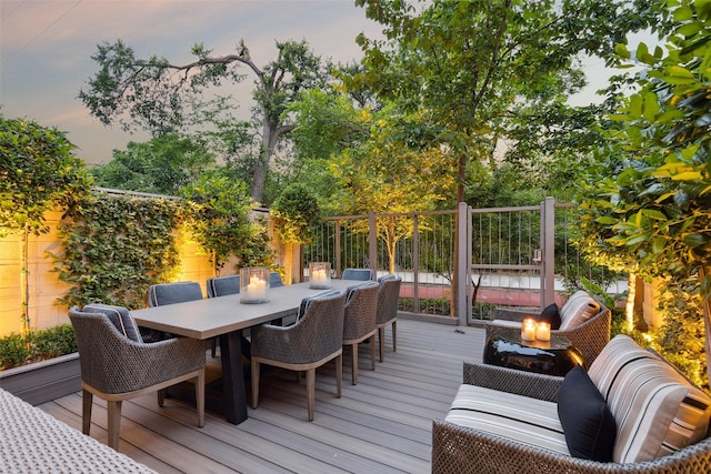 deck at dusk with an outdoor fire pit and outdoor dining area