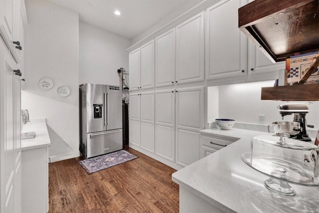 kitchen with high end refrigerator, white cabinetry, dark wood-type flooring, light countertops, and exhaust hood