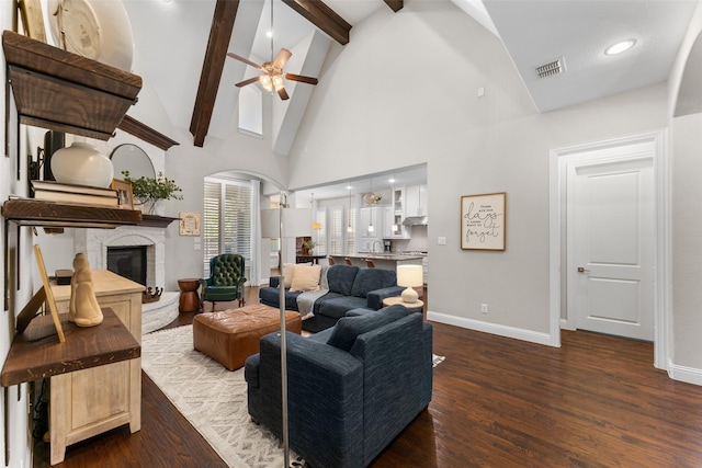 12092 Burnt Prairie Ln, Frisco, TX 75035 - living room with dark wood-style flooring, a glass covered fireplace, beamed ceiling, ceiling fan, and baseboards