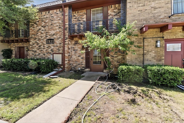 1811 E Grauwyler Rd Unit 138, Irving, TX 75061 - doorway to property featuring a balcony, brick siding, and a yard