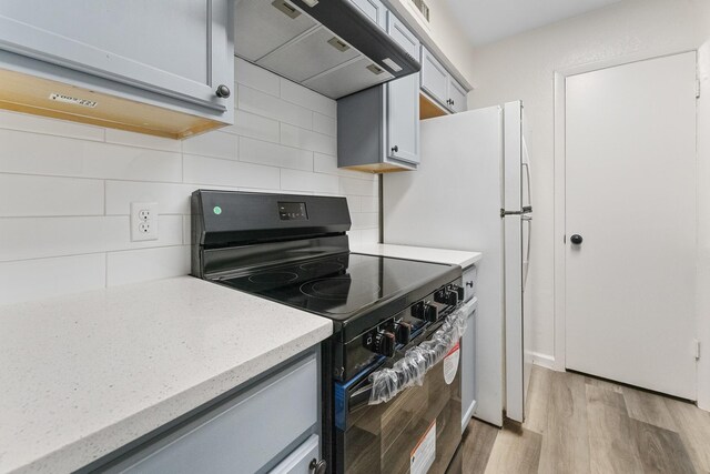 1811 E Grauwyler Rd Unit 138, Irving, TX 75061 - kitchen with black electric range, range hood, light wood-style flooring, tasteful backsplash, and light stone countertops
