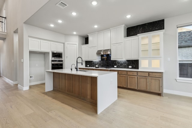 2921 Citation Rd, Celina, TX 75009 - kitchen featuring appliances with stainless steel finishes, under cabinet range hood, light wood-style floors, tasteful backsplash, and recessed lighting