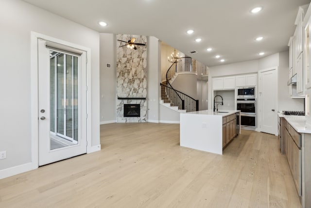 2921 Citation Rd, Celina, TX 75009 - kitchen with appliances with stainless steel finishes, light wood-style floors, white cabinets, a kitchen island with sink, and a ceiling fan