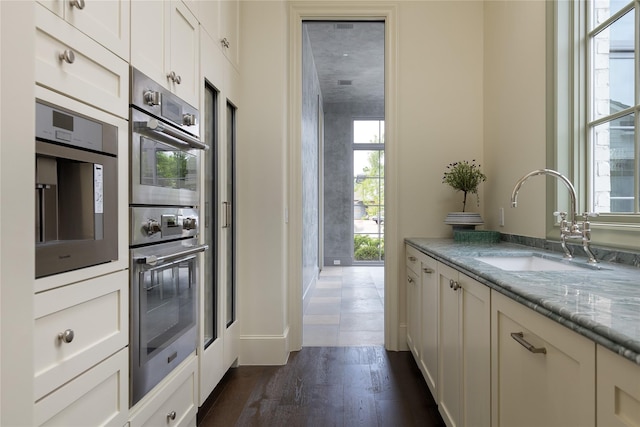 5610 Lobello, Dallas, TX 75229 - kitchen featuring a sink, dark wood finished floors, stainless steel double oven, light stone countertops, and white cabinets