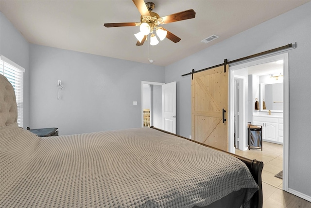 5061 Britton Ridge Ln, Fort Worth, TX 76179 - bedroom featuring a barn door, light tile patterned flooring, ceiling fan, and ensuite bath
