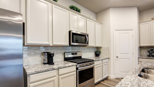 7436 Palisades Dr, Rowlett, TX 75088 - kitchen with appliances with stainless steel finishes, tasteful backsplash, light wood-style flooring, and light stone counters