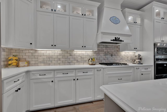 150 St Andrews Ln, Benton, LA 71006 - kitchen with appliances with stainless steel finishes, custom range hood, white cabinets, light countertops, and glass insert cabinets
