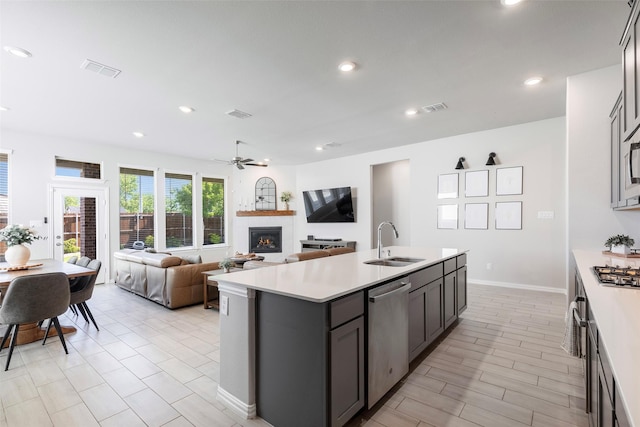 1106 Sassafras Dr, Princeton, TX 75407 - kitchen with stainless steel appliances, a sink, a lit fireplace, light countertops, and recessed lighting