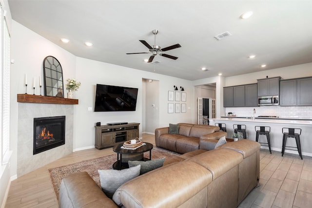 1106 Sassafras Dr, Princeton, TX 75407 - living room with light wood-style flooring, ceiling fan, recessed lighting, a tiled fireplace, and baseboards