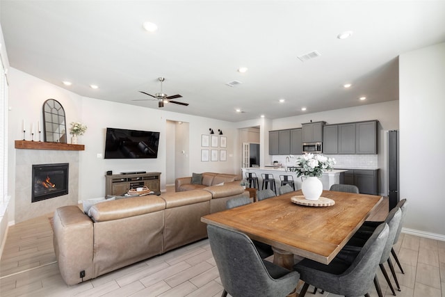 1106 Sassafras Dr, Princeton, TX 75407 - dining area featuring wood tiled floors, a ceiling fan, a tiled fireplace, recessed lighting, and baseboards