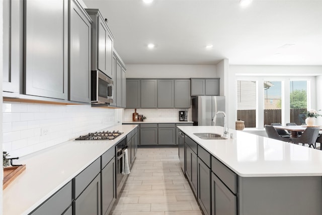 1106 Sassafras Dr, Princeton, TX 75407 - kitchen featuring gray cabinetry, a sink, appliances with stainless steel finishes, tasteful backsplash, and a kitchen island with sink