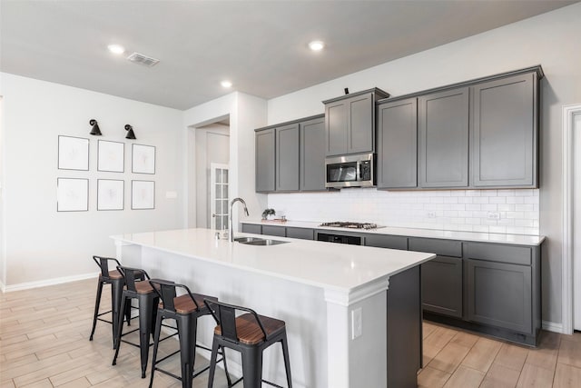 1106 Sassafras Dr, Princeton, TX 75407 - kitchen with appliances with stainless steel finishes, a sink, decorative backsplash, a kitchen island with sink, and a breakfast bar