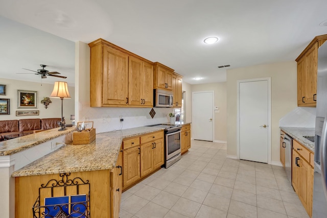 1521 Rice Rd Unit A101, Tyler, TX 75703 - kitchen featuring appliances with stainless steel finishes, a peninsula, ceiling fan, light stone countertops, and backsplash