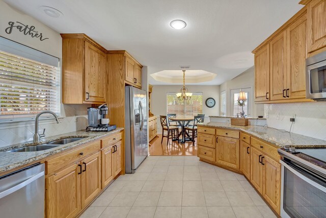 1521 Rice Rd Unit A101, Tyler, TX 75703 - kitchen with stainless steel appliances, a sink, tasteful backsplash, and light stone counters