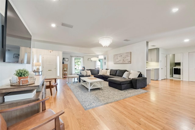 living area with light wood-style flooring, recessed lighting, a chandelier, and washer / dryer