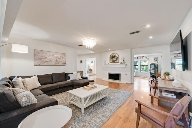 living room with light wood-style flooring, recessed lighting, a fireplace, and a chandelier