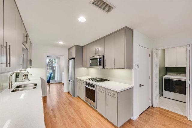 kitchen featuring stainless steel appliances, a sink, gray cabinetry, light wood-style floors, and recessed lighting