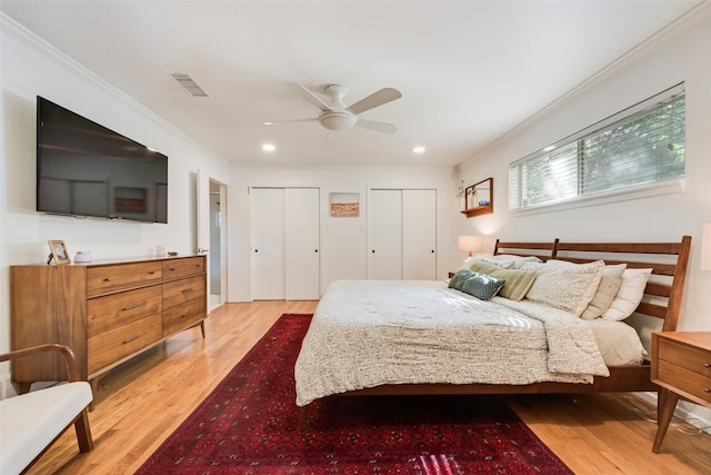 bedroom featuring ornamental molding, two closets, light wood finished floors, recessed lighting, and ceiling fan