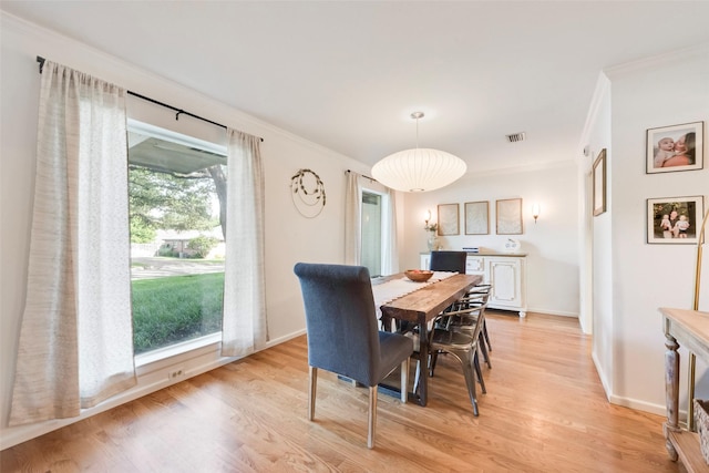 dining space featuring ornamental molding, light wood finished floors, and baseboards