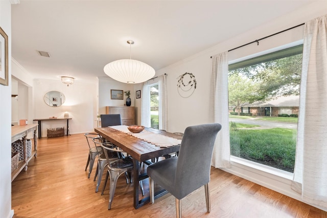 dining room with plenty of natural light, light wood-style floors, baseboards, and ornamental molding