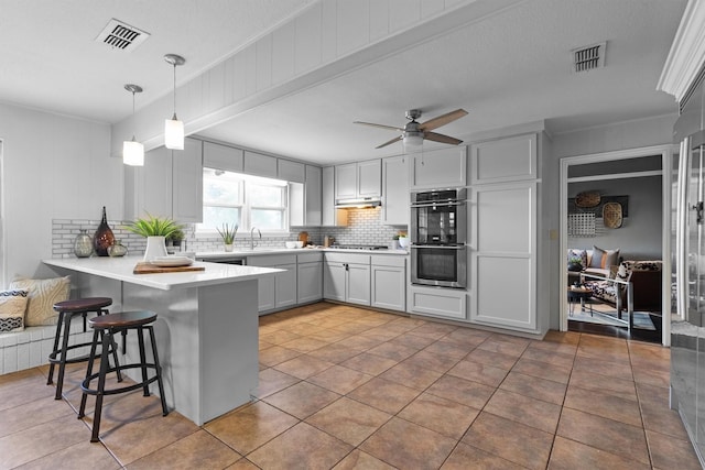 919 Old Justin Rd, Argyle, TX 76226 - kitchen featuring appliances with stainless steel finishes, a peninsula, decorative backsplash, under cabinet range hood, and a breakfast bar area