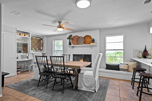 919 Old Justin Rd, Argyle, TX 76226 - tiled dining room featuring a ceiling fan, a brick fireplace, and a textured ceiling