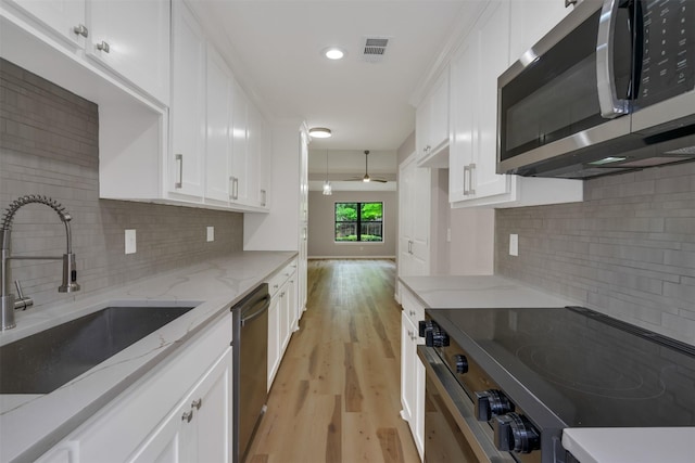 13788 Brookgreen Cir, Dallas, TX 75240 - kitchen featuring appliances with stainless steel finishes, a sink, white cabinets, light wood finished floors, and recessed lighting