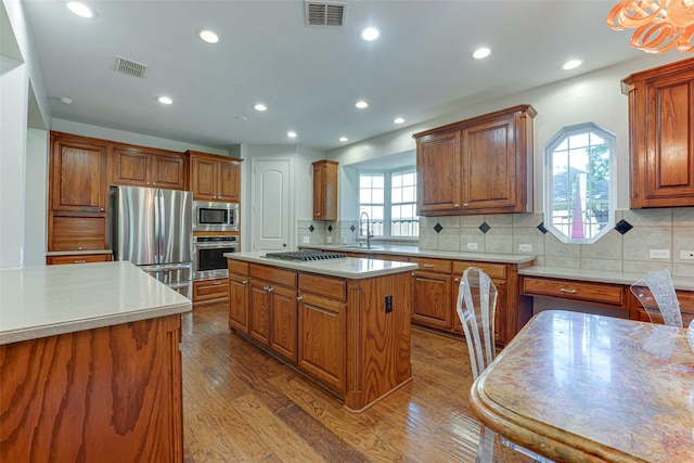 2621 Elmbrook Dr, Carrollton, TX 75010 - kitchen featuring stainless steel appliances, brown cabinets, light countertops, a center island, and recessed lighting