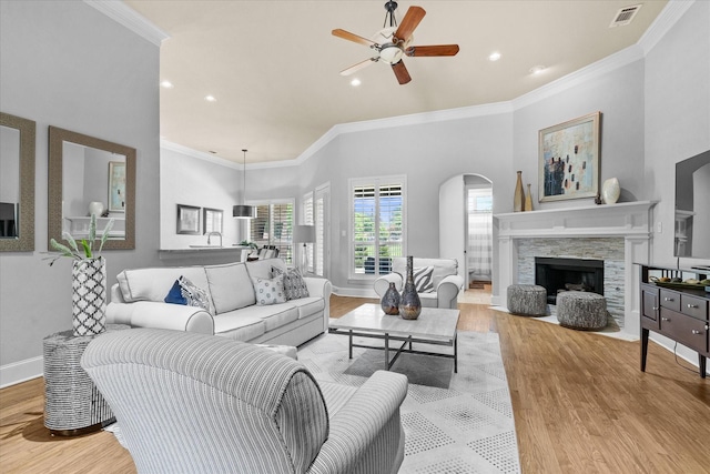 living area with wood finished floors, ceiling fan, crown molding, recessed lighting, and arched walkways