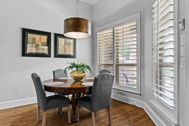 dining room featuring dark wood-type flooring, ornamental molding, and baseboards