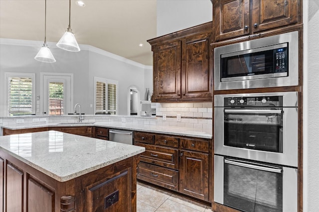 kitchen with a sink, stainless steel appliances, ornamental molding, light stone countertops, and decorative backsplash